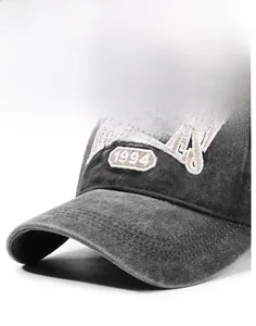 Detailed macro view of embroidered vintage lettering on dark grey washed baseball cap