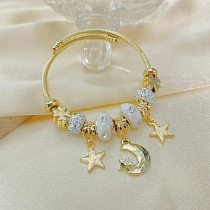 Detailed close-up of golden wire bracelet with star and moon charms and crystals