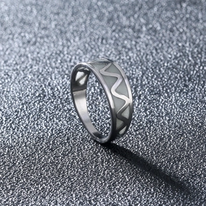 Detailed close-up of wavy stainless steel ring featuring luminous green inlay and silver finish