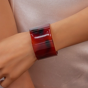 Close-up of a wide amber resin cuff bracelet featuring natural marbled texture on wrist