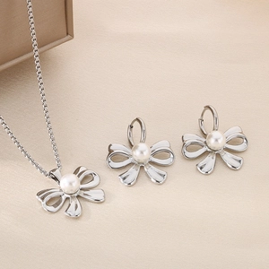 Close-up of silver bow jewelry set with white pearls including necklace and earrings
