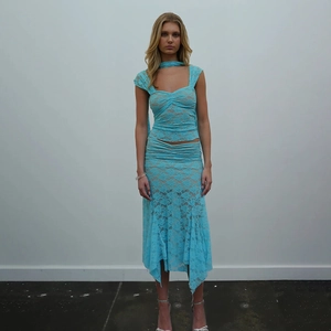 Détail d'un ensemble deux pièces en dentelle turquoise avec haut licou et jupe midi