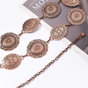 Détail de la chaîne de taille en métal bronze avec conchos embossés et fermoir à crochet