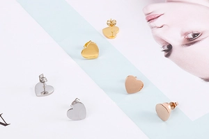 Detailed view of heart-shaped stud earrings in gold, silver, and rose gold finishes