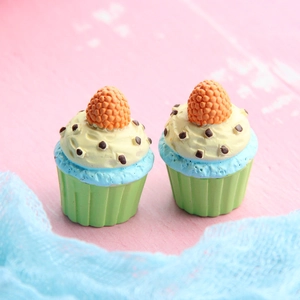 Macro shot of two resin miniature cupcakes with blue frosting and chocolate sprinkles