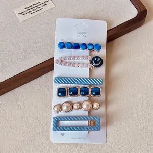Detail view of a 6-piece blue rhinestone and pearl hair clip set on a white card display