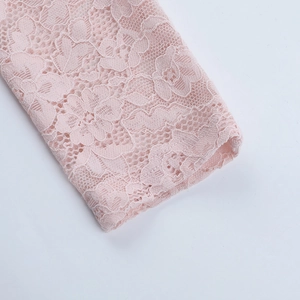 Close-up of pink lace cuff detailing with delicate floral patterns and scalloped edges