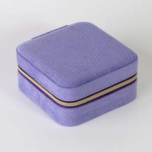 Top view of purple square fabric jewelry box with textured finish and gold zipper detail