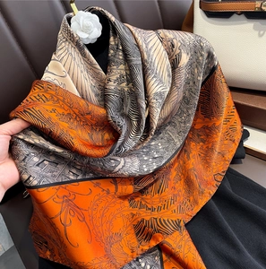 Carré de soie classique avec motif floral orange drapé élégamment sur un support