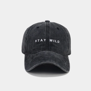Dettaglio del ricamo bianco 'STAY WILD' su cappello in denim lavato color antracite