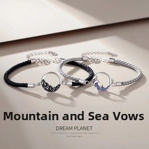 Macro detail of mountain and wave enamel charms on magnetic couple braided bracelets