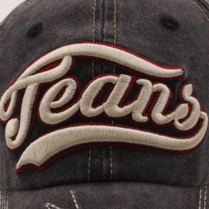Detailed close-up of 3D Jeans embroidery on washed denim baseball cap with distressed edge