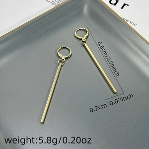 Detail showing long gold bar earrings with dimensions 6.6cm on a gray textured plate