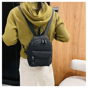Rear view of a black nylon backpack on a model wearing a lime green knit sweater