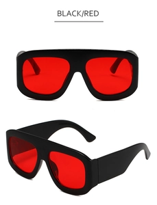 Detail view of large square black frame sunglasses with vibrant red tinted lenses