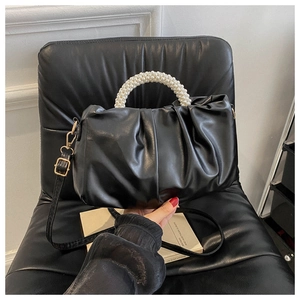 Close-up of black pleated crossbody bag featuring a luxury pearl handle and leather texture