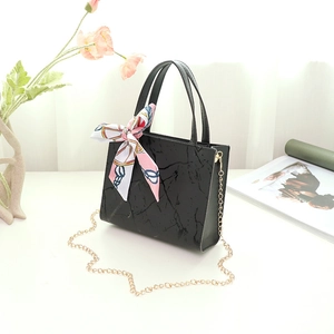Detail of black marble textured PU leather tote bag with silk scarf and gold chain strap