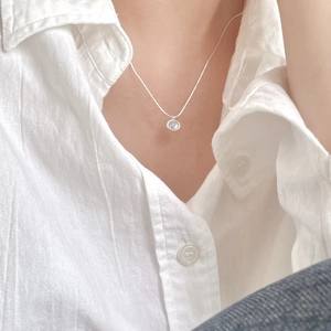 Close-up of sterling silver necklace with iridescent round pendant on model neck
