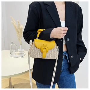 Detail of hand-woven straw crossbody bag with yellow leather buckle and shoulder strap