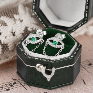 Detailed close-up of S925 silver evil eye earring with green stones in a velvet box