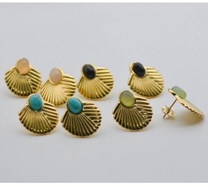 Macro detail of bohemian shell-shaped gold plated earrings with varied natural stones
