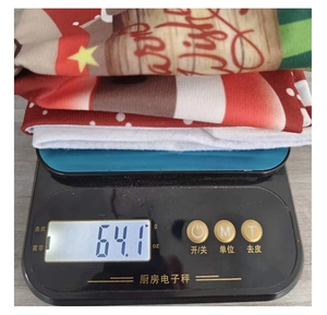 Détail d'une housse de chaise Merry Christmas sur une balance pesant 64,1 grammes