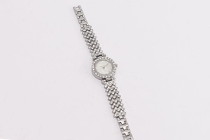 Detailed view of women's silver watch with rhinestone strap and pearl dial on white