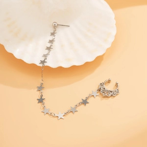 Detail of silver star chain earring connector with a hollow pattern ear cuff on a shell