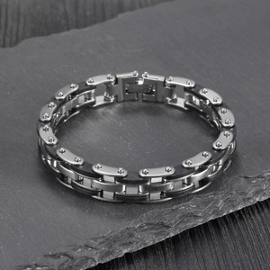 Close-up of industrial style men's stainless steel and black silicone bracelet on stone