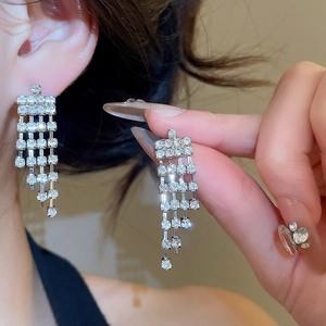 Close-up of silver-tone tassel earrings with multi-row rhinestones on model's ear