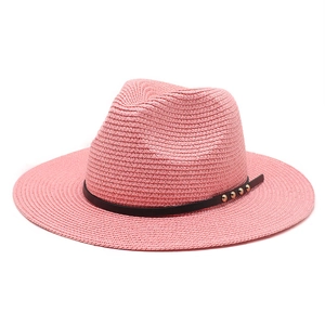 Detailansicht eines rosa Strohhutes mit schwarzem Kunstlederband und goldenen Nieten