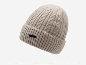 Detailed view of beige knit beanie featuring cable pattern and ribbed folded brim