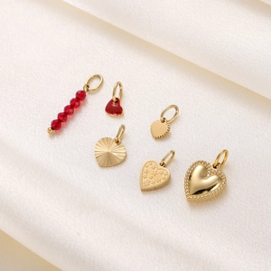 Detailed macro view of assorted gold heart pendants and red charms on silk fabric
