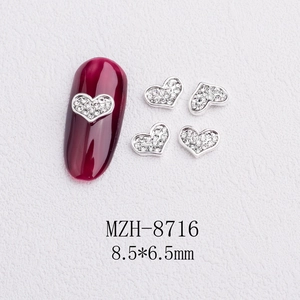 Detail view of 8.5x6.5mm silver heart nail charms with rhinestones on red cat eye nail art