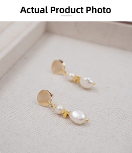 Close-up of baroque pearl earrings with textured golden metal components and matte finish