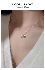 Detailed view of the S925 silver bow pendant necklace worn by a model on the neckline