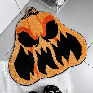 Close-up of a pumpkin-shaped Halloween doormat with orange and black spooky face patterns