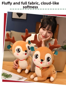 Close-up of cute plush reindeer toys with red collars and golden bells on a wooden desk