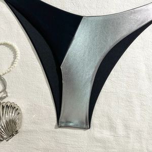 Detail shot of black matte and metallic silver patchwork bikini bottom on white fabric