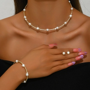 Close-up of gold pearl choker and matching earrings set on model for formal wear