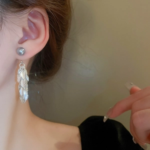 Détail des boucles d'oreilles à pompons feuilles argentées avec perle grise sur mannequin