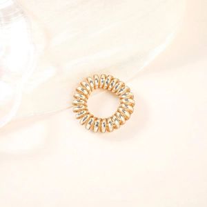 Detailed view of champagne gold spiral hair tie on soft beige satin fabric texture
