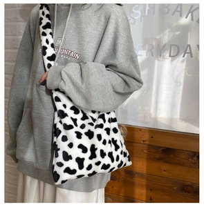 Detailed view of women's plush cow print shoulder bag worn in a cozy indoor setting