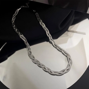 Sleek silver stainless steel braided blade chain necklace reflecting on a mirror surface