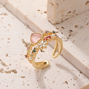 Vintage gold open ring with pink gem, colorful stones and pearls on stone background