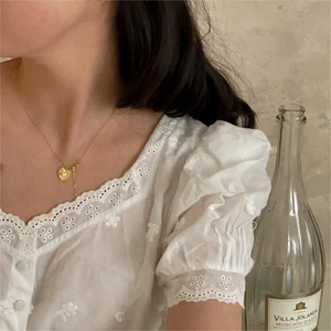 Detailed view of a gold wrinkled heart pendant necklace with a zircon stone on a model