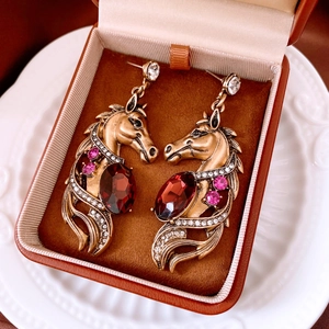 Macro view of vintage horse-head earrings with red gemstones and pink crystals