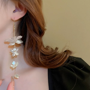 Close-up of model wearing elegant long white flower tassel earrings in minimalist style