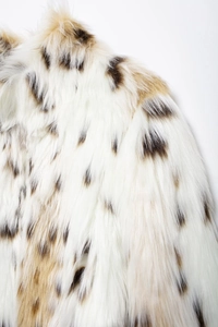 Close-up of soft white faux fur coat with brown leopard spots and plush texture
