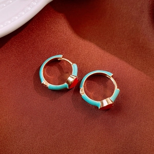 Macro shot of gold vintage hoop earrings with green enamel and red heart accents